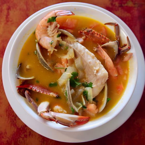 Hearty seafood soup with shrimp, fish, crab, and clams in a golden broth.